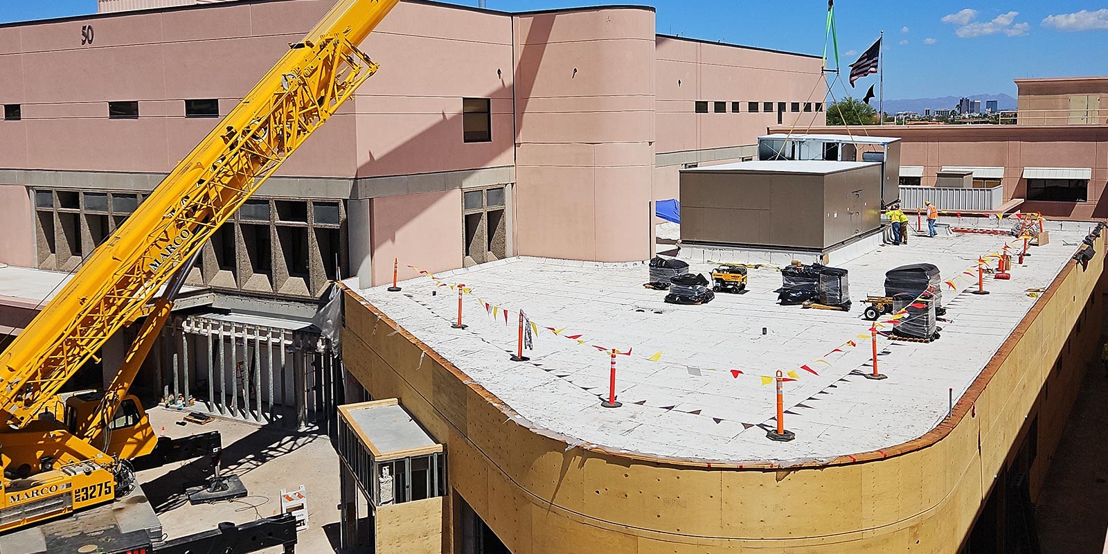 Crane setting rooftop mechanical equipment on a commercial building under construction